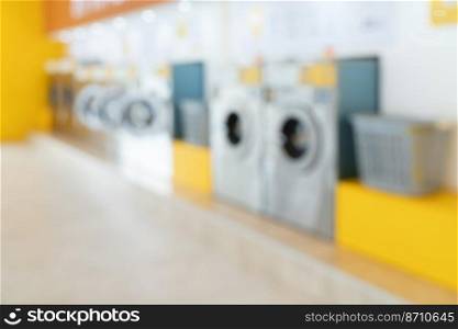 Blur background of of qualified coin-operated washing machines in a public store. Concept of a self service commercial laundry and drying machine in a public room.. Blur background of qualified coin-operated washing machines in a public store.