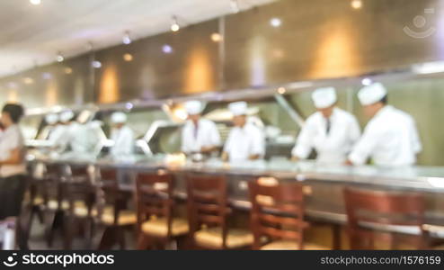 Blur background of sushi restaurant with many chef making sushi behind the sushi bar. Traditional Japanese cuisine and small business in Tokyo, Japan.