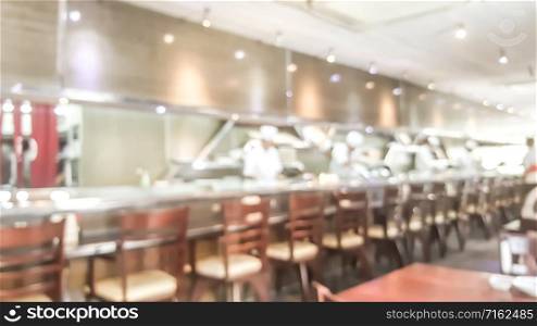 Blur background of sushi restaurant with many chef making sushi behind the sushi bar. Traditional Japanese cuisine and small business in Tokyo, Japan.