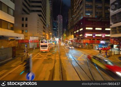 Blur background of tram or bus view at night. Crowd of people on street of Central district. Transportation for tourists visiting the urban city in travel trip or holiday. Hong Kong Downtown, China