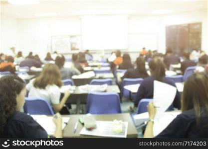 Blur background of university students does quizzes, test or studies from the teacher in a large lecture room. Students in uniform attending exam classroom educational school.