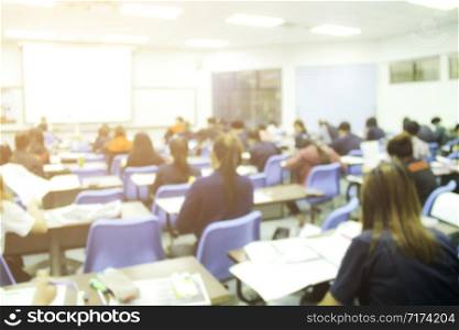 Blur background of university students does quizzes, test or studies from the teacher in a large lecture room. Students in uniform attending exam classroom educational school.