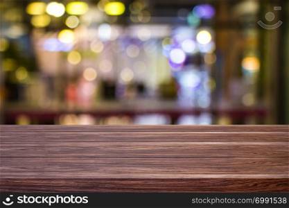 Blur cafe restaurant or coffee shop empty of dark wood table with blurred light gold bokeh abstract background for montage product display or design.
