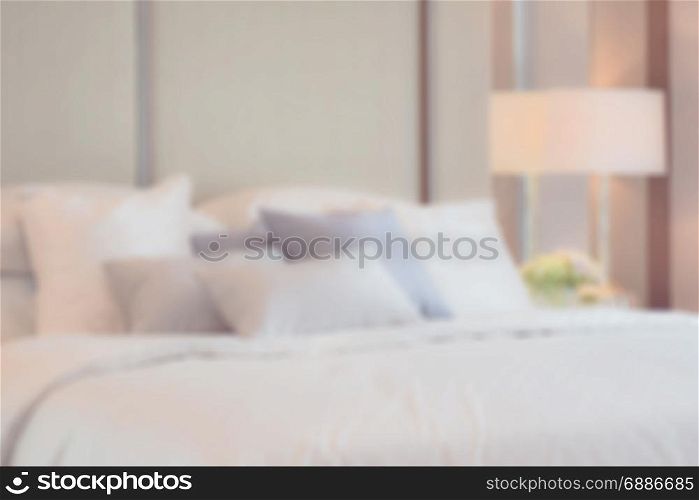 blur image of classic bedroom interior with pillows and reading lamp on bedside table