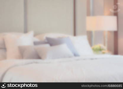 blur image of classic bedroom interior with pillows and reading lamp on bedside table