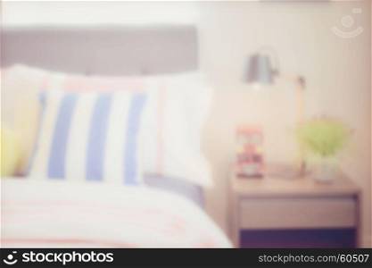 blur image of colorful pillows and reading lamp on bedside table