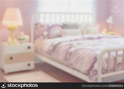 blur image of cozy bedroom interior with pillows and reading lamp on bedside table