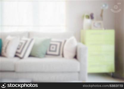 blur image of cozy sofa with geometric pattern pillows and green sideboard in living corner