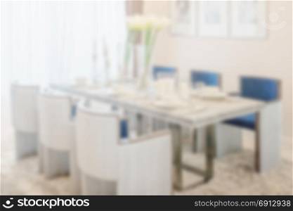 blur image of dining table and comfortable chairs in modern home with elegant table setting