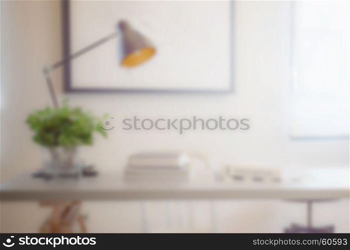 blur image of work table with book, lamp and vase at home