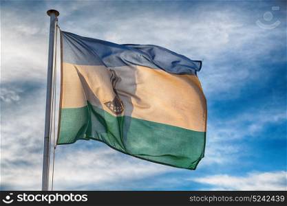 blur in lesotho waving national flag in the cloudy sky
