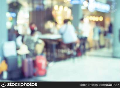 Blur passengers with luggage sitting in airport coffee shop for background