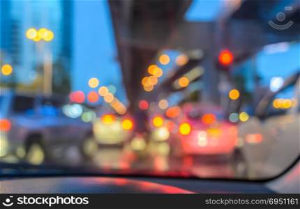 Blurred abstract background of car seen through windscreen with bokeh lights at twilight