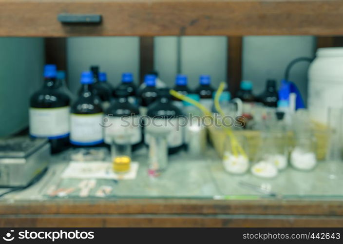 Blurred abstract background of old wooden chemical hood with reagent bottles in laboratory