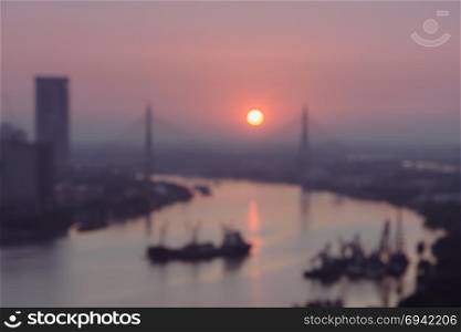 Blurred aerial view of riverside city skyline on golden warm sunrise over the cable bridge in Bangkok, Thailand