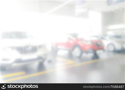 Blurred background of dealership with new cars for sale in the row