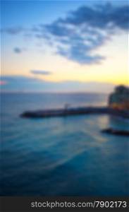 Blurred background of long pier on the sea, at sunset light, vertical image
