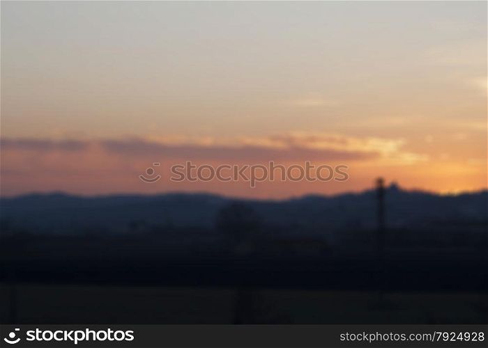 Blurred background of sunset over fields and small town, horizontal image
