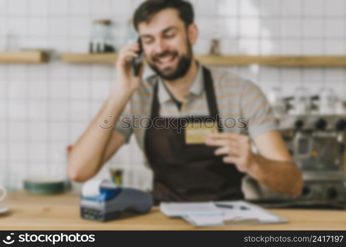 blurred barista with credit card speaking smartphone