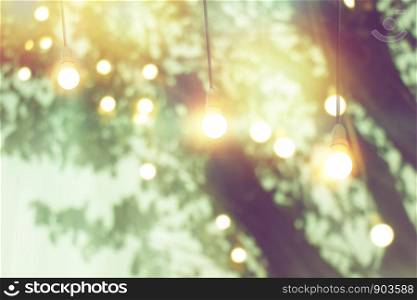 blurred bokeh light on sunset with yellow string lights decor in tree