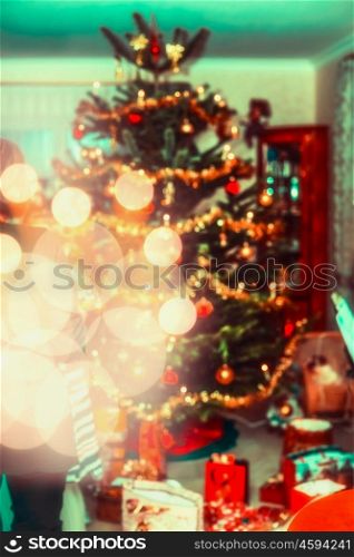 Blurred Christmas home scene with decorated Christmas tree, gifts and festive bokeh lighting