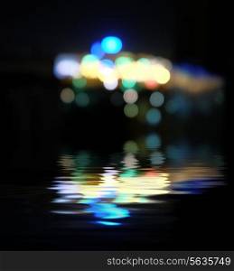 Blurred city at night, bokeh background. Reflection of colorful lights in water and a lot of copyspace