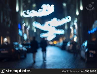 Blurred city at night. Bokeh. Beautiful abstract background with defocused buildings, cars, city lights, people. Colorful bokeh background with urban night scene. Design. Concept backdrop. Vintage . Blurred city at night. Bokeh