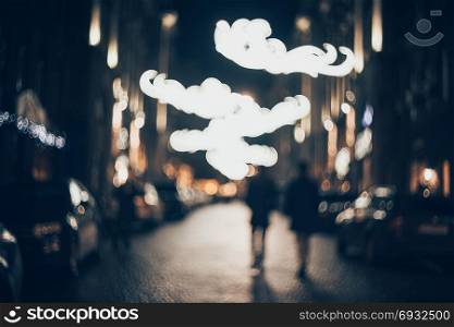 Blurred city at night. Bokeh. Beautiful abstract background with defocused buildings, cars, city lights, people. Colorful bokeh background with urban night scene. Design. Concept backdrop. Vintage . Blurred city at night. Bokeh