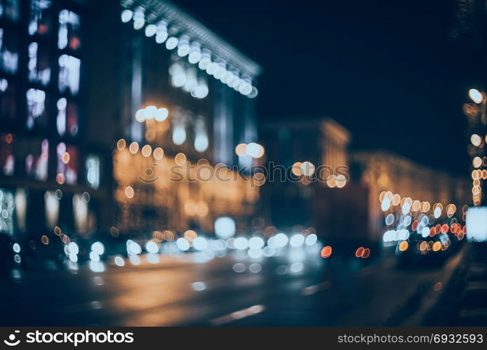 Blurred city at night. Bokeh. Beautiful abstract background with defocused buildings, cars, city lights, people. Colorful bokeh background with urban night scene. Design. Concept backdrop. Vintage . Blurred city at night. Bokeh