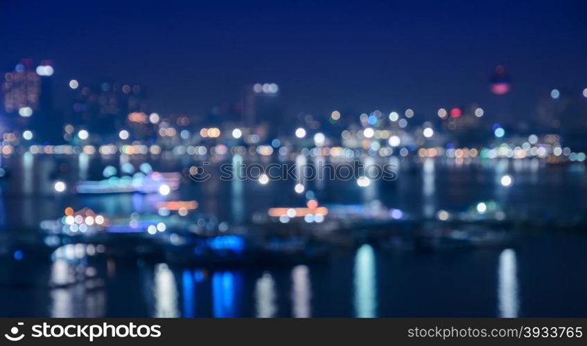 Blurred city skyline lights illuminated at night with reflection on river