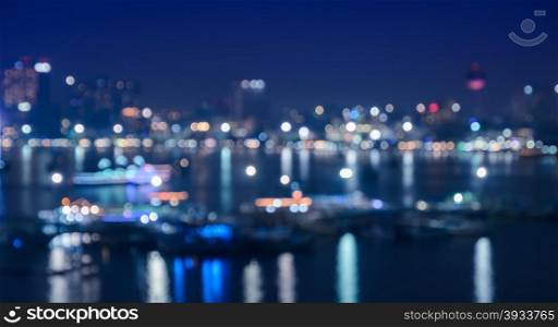 Blurred city skyline lights illuminated at night with reflection on river