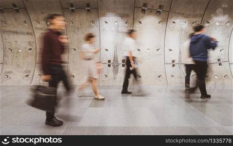 Blurred crowd of unrecognizable business people walking in modern subway tunnel in rush hour working day, blur business and transportation concept,