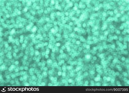Blurred decorative sequins. Background image with shiny bokeh lights from small elements that reflect light turquoise color. A huge amount of decorative sequins. Background image with shiny bokeh lights from small elements