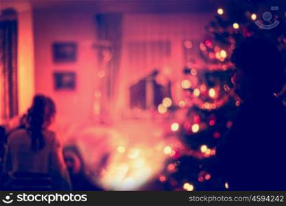 Blurred home Christmas scene with Christmas tree, gifts , festive bokeh lighting and silhouette of girl