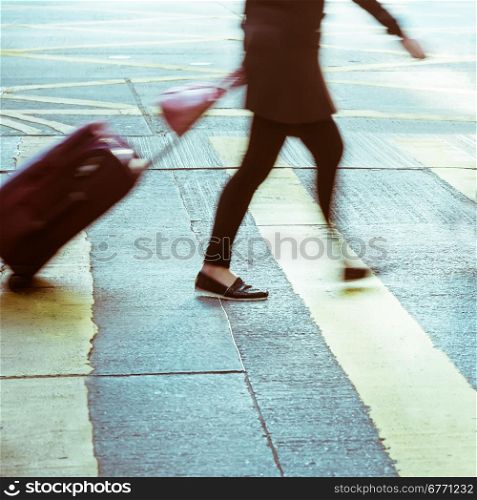 Blurred image of pedestrian with travel bag walking on crossroad at city street. Hong Kong. Art toning abstract urban background