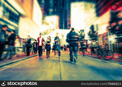 Blurred image of people moving in crowded night city street. Art toning abstract urban background. Hong Kong