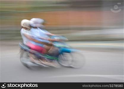Blurred image of people riding a motorbike in Bali