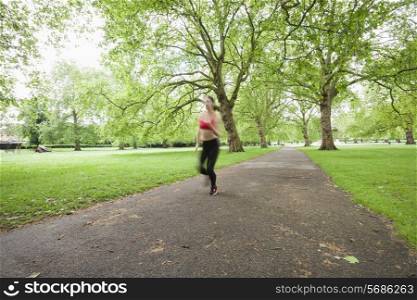 Blurred motion of woman jogging in park