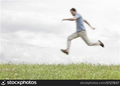 Blurred motion of young man jumping in park against sky