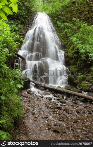 Blurred motion shot of remote waterfall splashing on rocks in forest