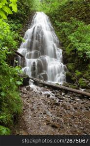Blurred motion shot of remote waterfall splashing on rocks in forest