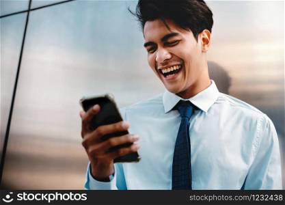 Blurred of a Happy Young Businessman Using Mobile Phone in the Urban City. Lifestyle of Modern People. Front View. Standing by the Wall.