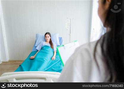 Blurred of female doctor therapeutic advising with positive emotions to Asian young female patient on Bed in hospital background