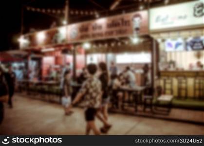 Blurred people walking in the night market.