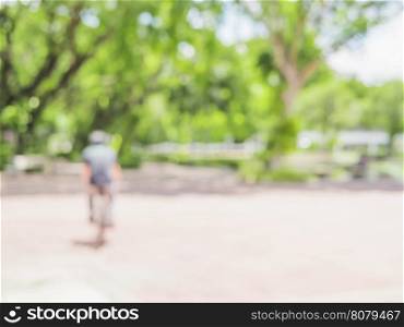 Blurred photo of bicycling buy with green tree background and white bokeh in the campus