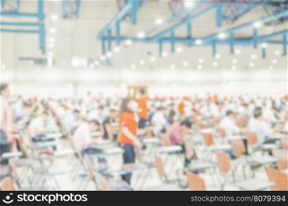 Blurred photo of crowded people taking examination in a big hall