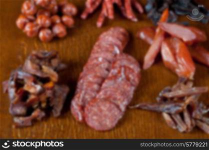 Blurred pronounced background of different sausage and meat on a celebratory table with spices and vegetables. meat and sausages
