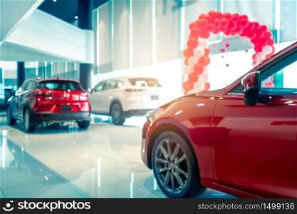Blurred rear view of red and white luxury SUV car parked in modern showroom for sale. SUV car with sports design in showroom. Car dealership. Coronavirus impact on automotive industry concept.