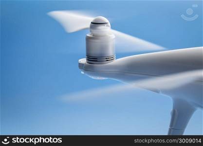 blurred spinning propellers of a drone against blue sky