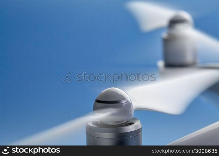 blurred spinning propellers of a drone against blue sky with a copy space